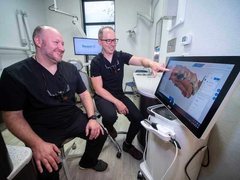The friendly staff at Beacon Hill Dental pointing at a digital image of a dental crown. 