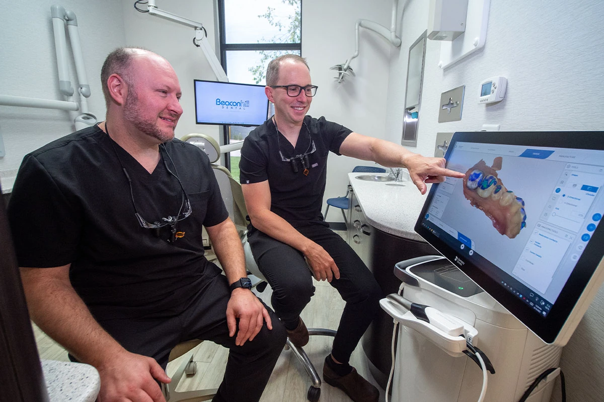 The friendly staff at Beacon Hill Dental pointing at a digital image of a dental crown.